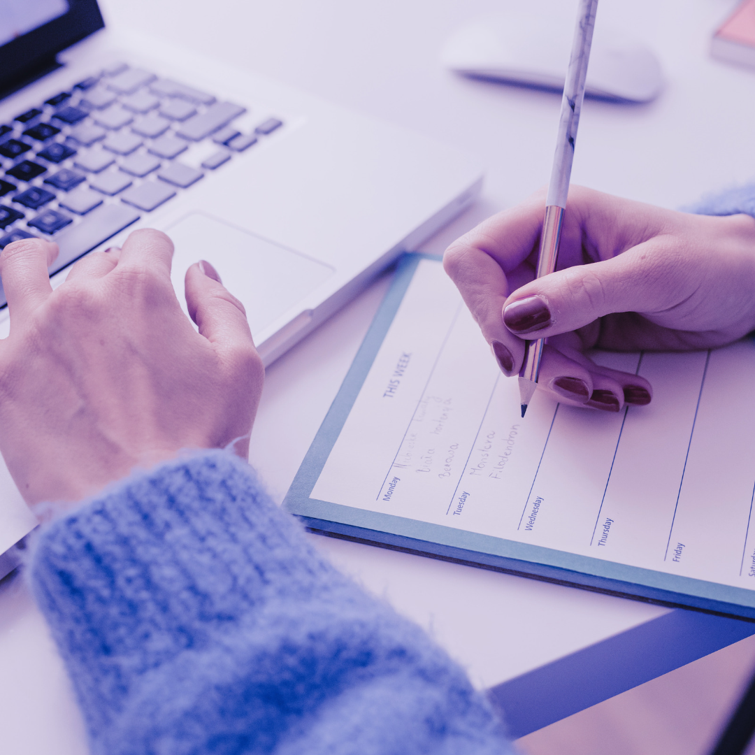 image of hands working at a desk filling in a planner